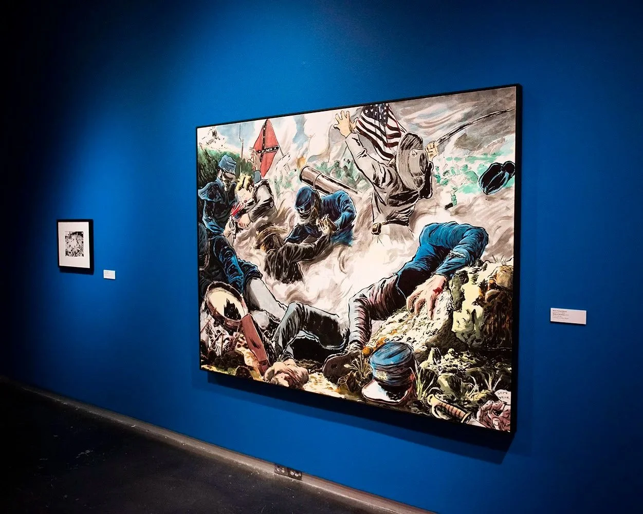Large painting titled Battle of Antietam by Mark Gibson hangs on a deep blue gallery wall, depicting a chaotic Civil War scene with fallen soldiers, flags, and swirling motion.