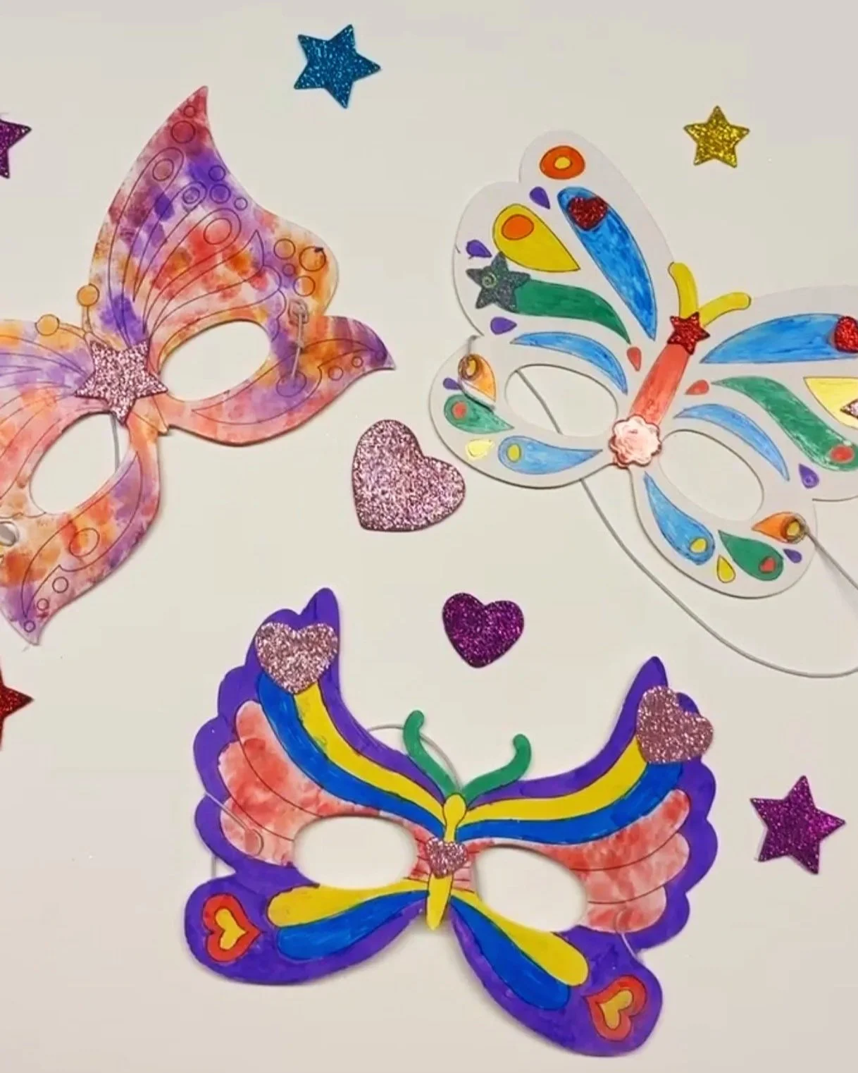Three colorful butterfly masks on a white table.