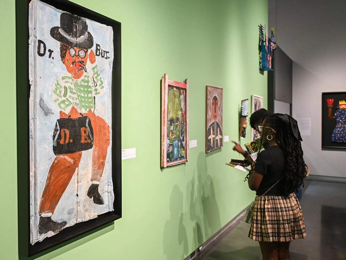 People looking at Folk Art in a gallery.