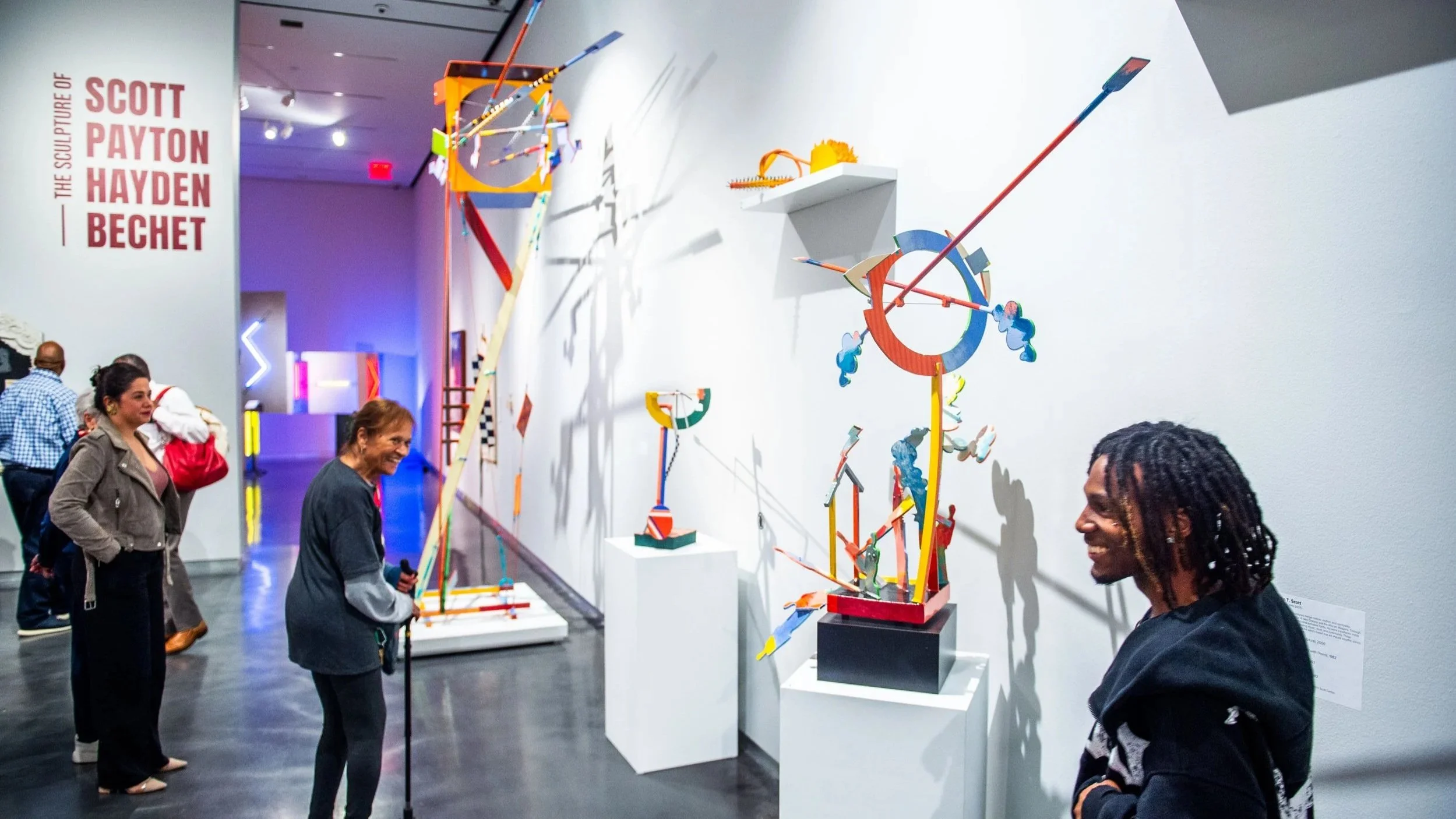 Visitors looking at colorful sculptures in the gallery.