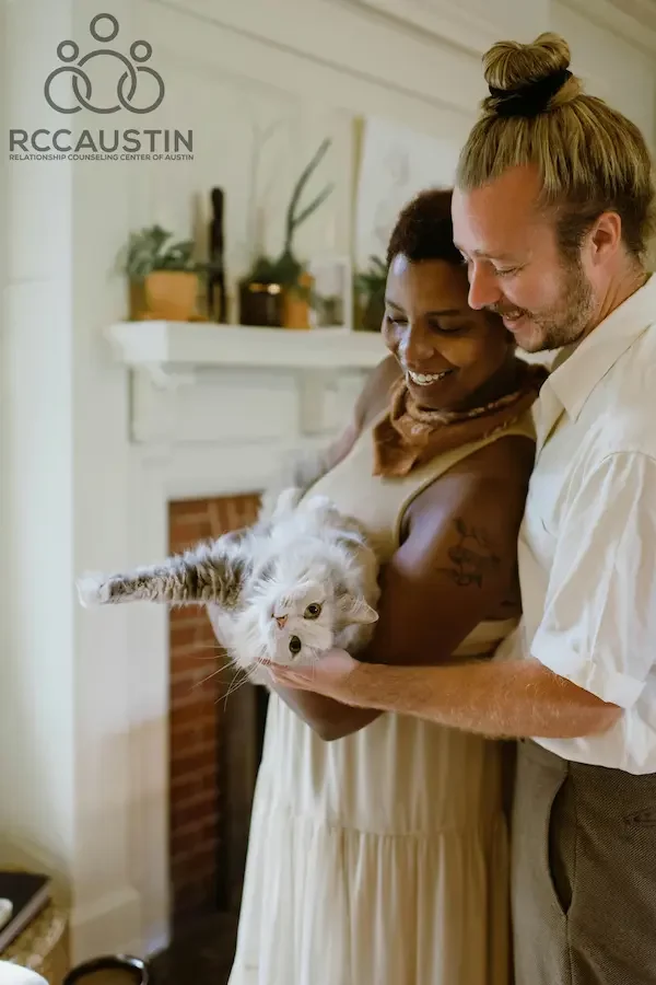 man and woman holding cat and smiling