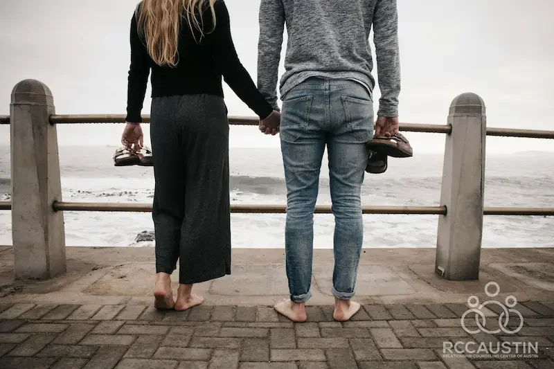 couple standing on board walk barefoot holding sandals