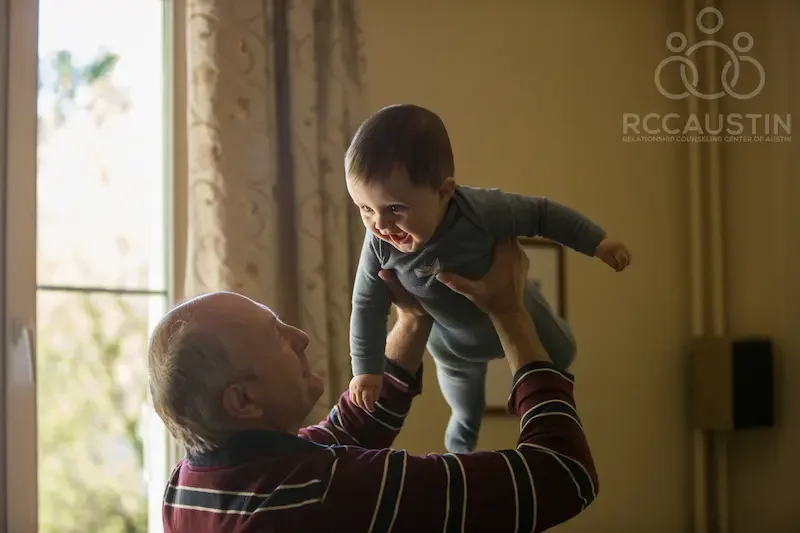 grandfather lifting smiling baby into the air