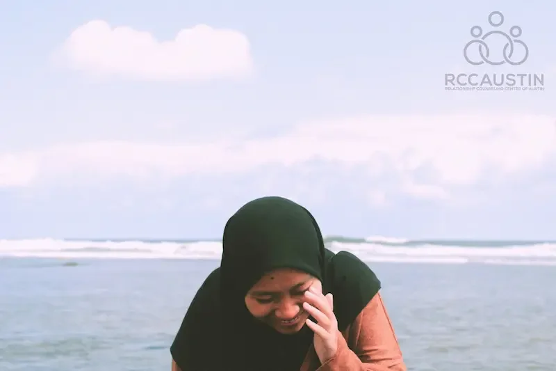 woman shielding face from photo on the beach