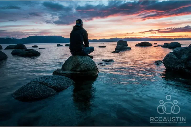 man sitting on rock looking out to ocean