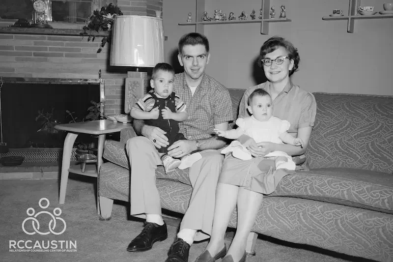 old black and white photo of couple sitting on sofa with two young children