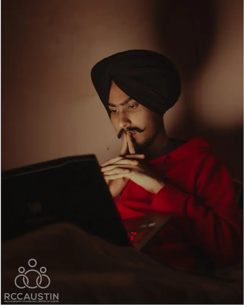 man sitting with laptop looking contemplative