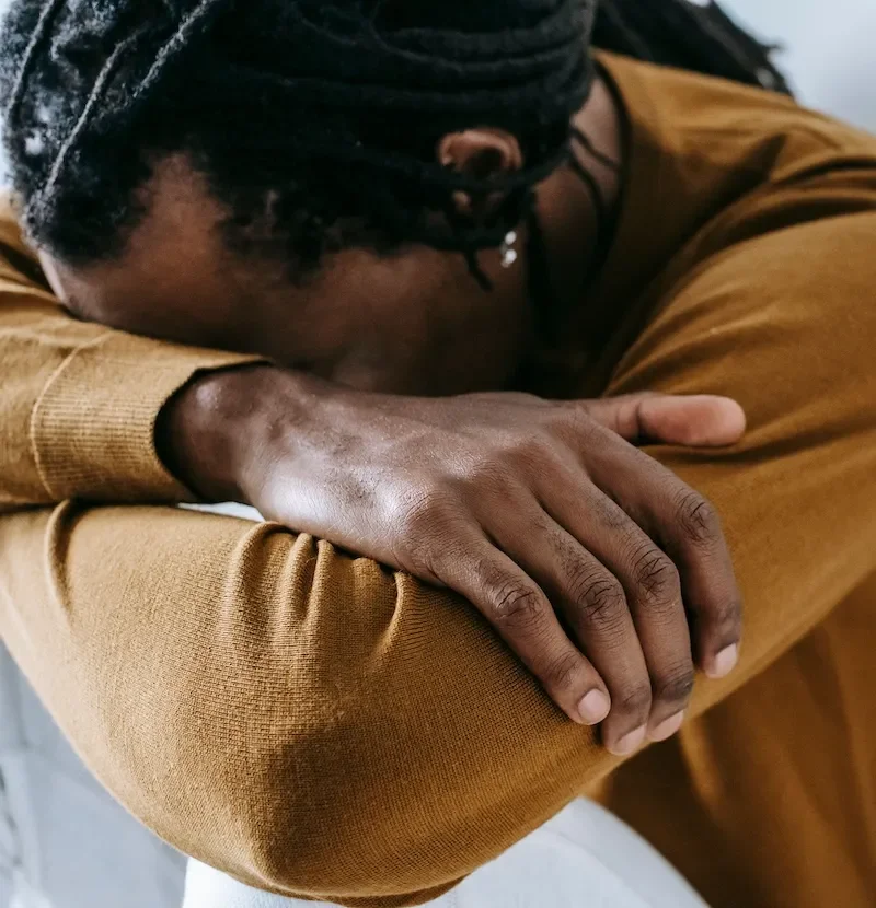 man hunched over with head on forearms