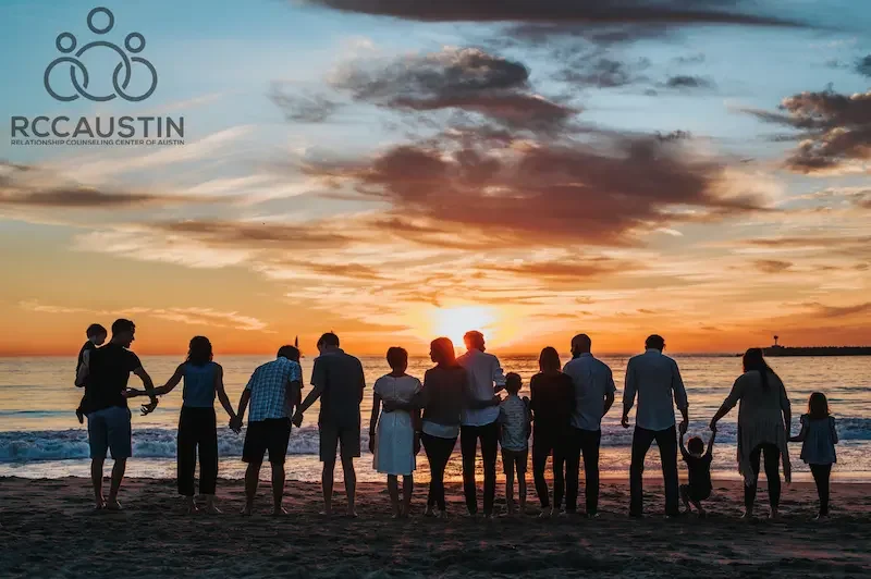 group of people on shoreline silhouetted against sunset