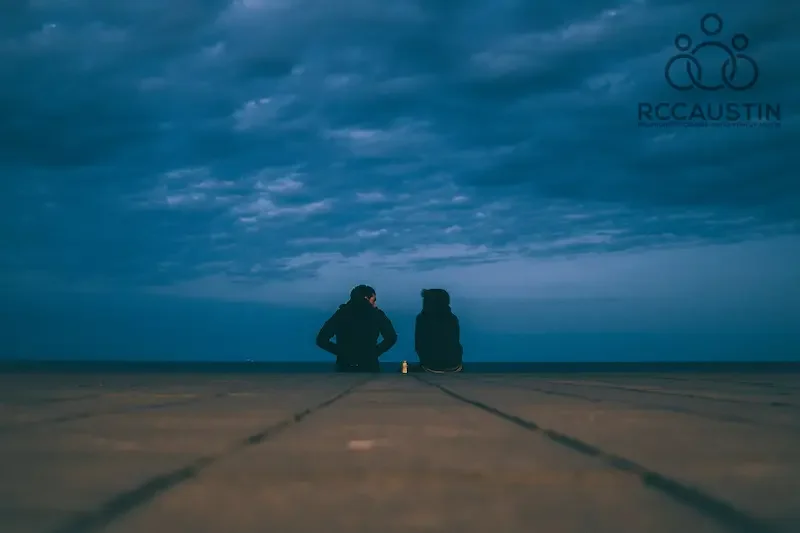 couple sitting on edge of boardwalk at dusk