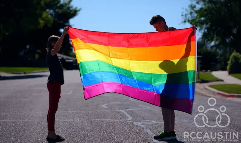 two people holding up large rainbow flag