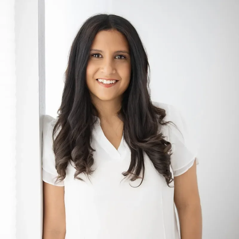 dina elmasri in white leaning against white wall