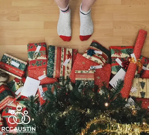 person standing by presents under christmas tree