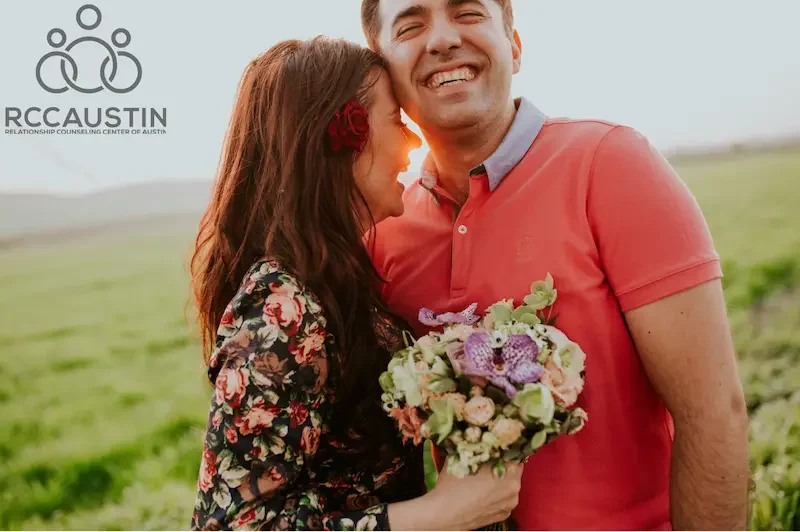 couple smiling in field holding bouquet