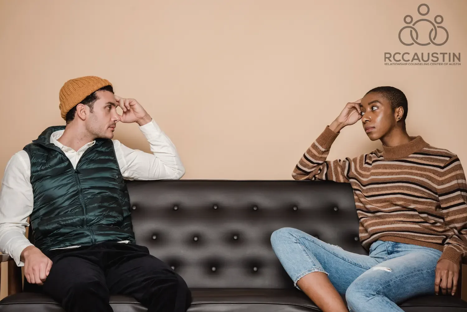 couple sitting on opposite sides of sofa with serious expressions