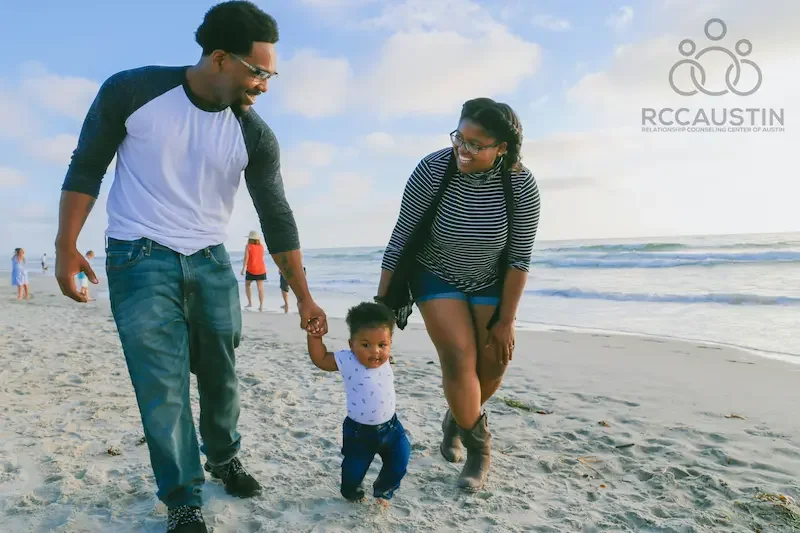 couple walking with young toddler at beach