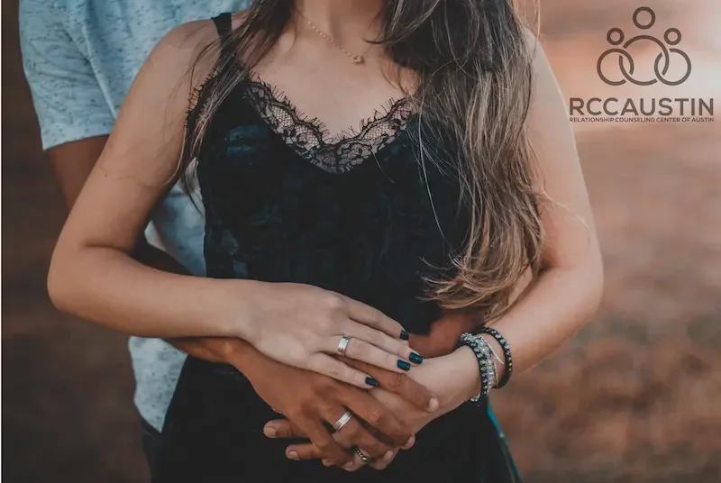 man standing behind woman with arms around waist