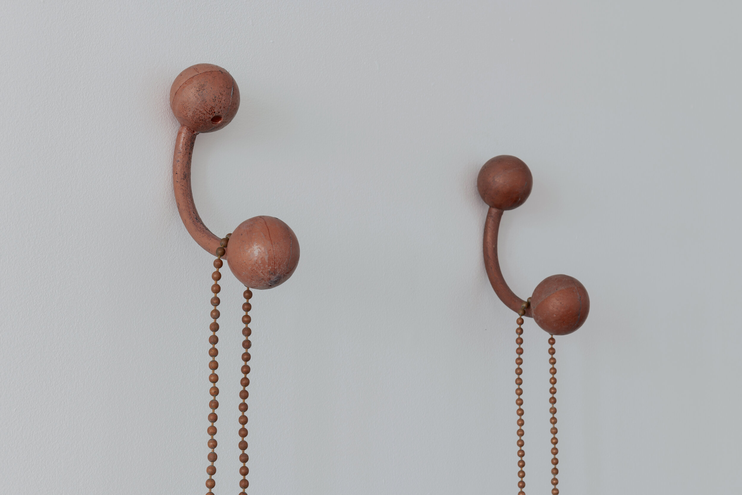  Detail view of:   Sessa Englund   Twin piercings with chain and butterflies (piercing series)  2021 Mahogany wood, cooper chain necklace, rust, mineral copper dust, cast resin 