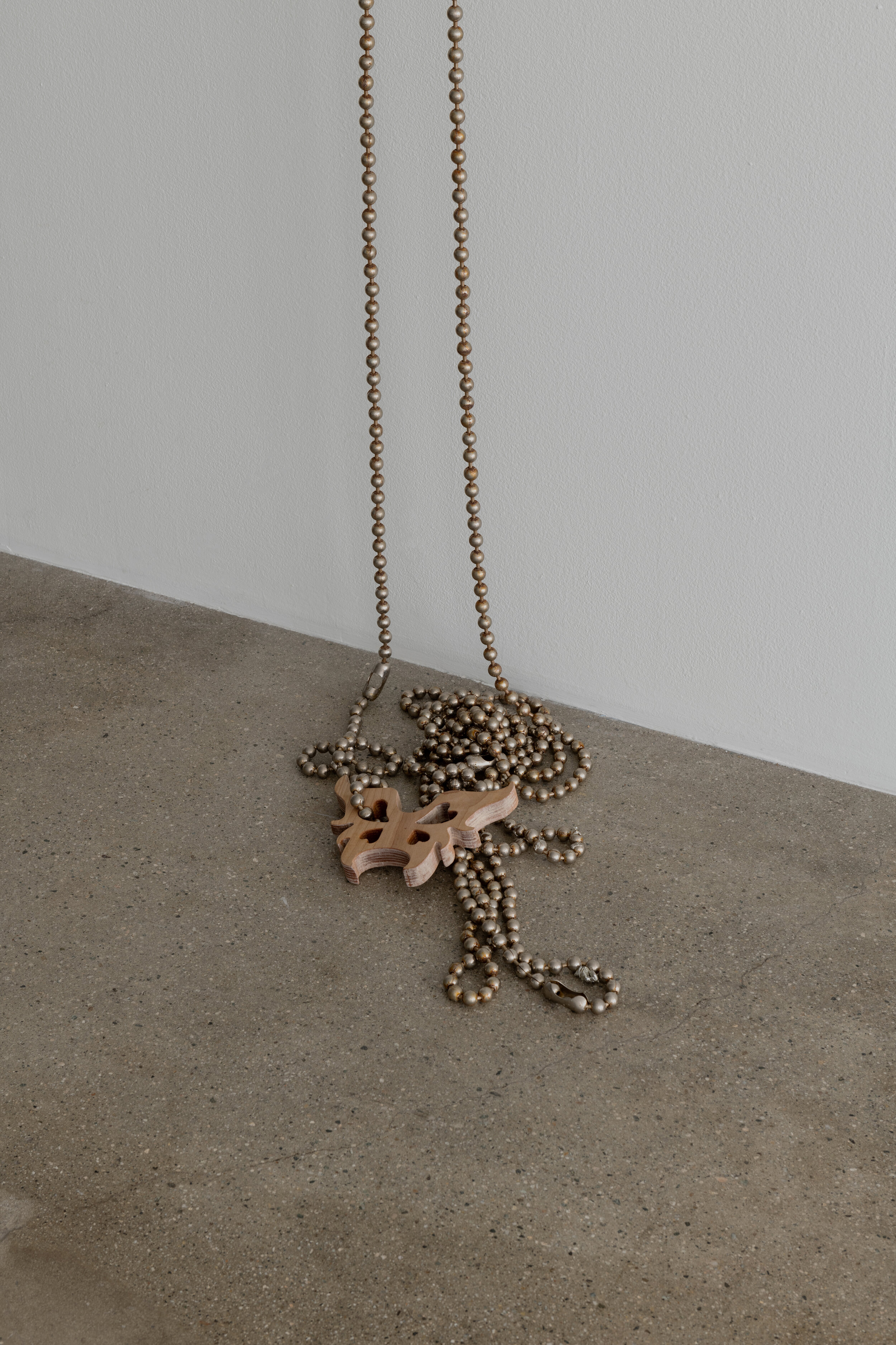 Detail view of   Sessa Englund   Single piercings with chain and butterflies (piercing series)  2021 Pine wood, stainless steel chain necklace, rust, alloy dust, cast resin 