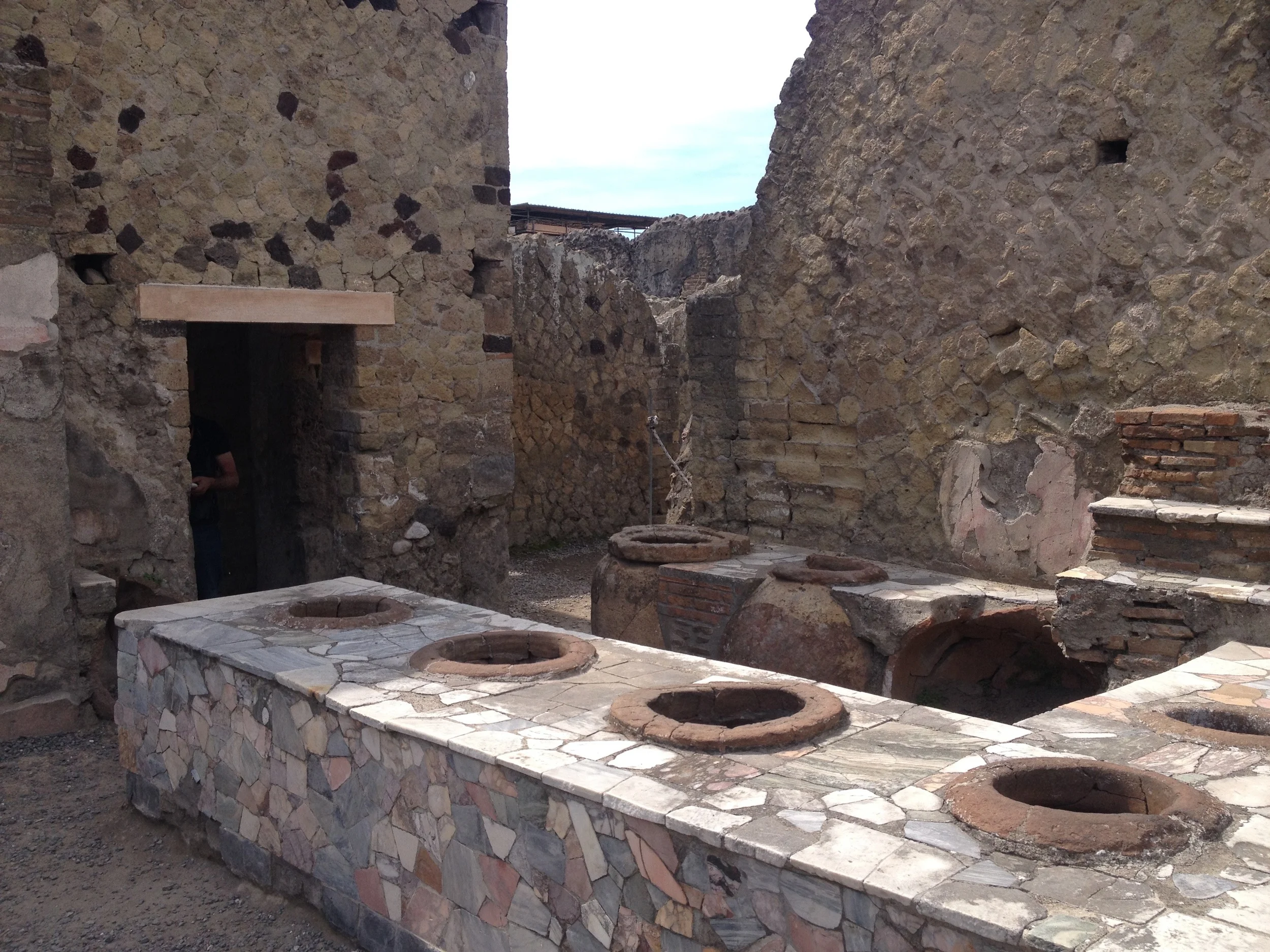 We complain about the ubiquitous fast food stands, but even in the years BC, fast food places were everywhere. Above is one of many snack bars in Herculaneum, the various large urns built into the counters no doubt serving up the Big Macs and french…