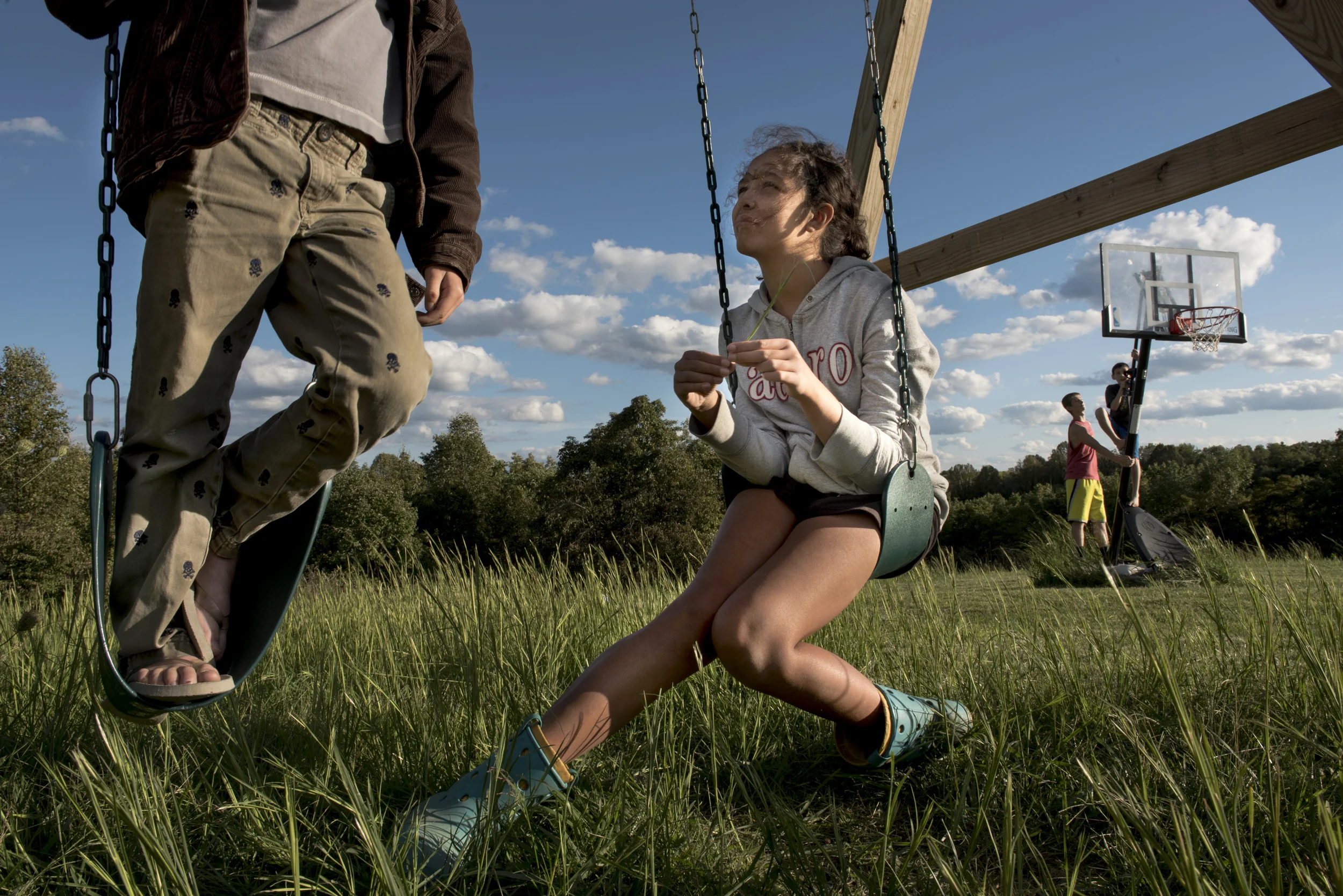   Mya Fuller, 16, middle, tells stories with her adoptive brother Liam, 11, left, as adoptive brothers Gabe, 14, and Keaton, 12, play on the basketball hoop in their backyard on September 14, 2015. The Fullers adopted seven children, including two pa