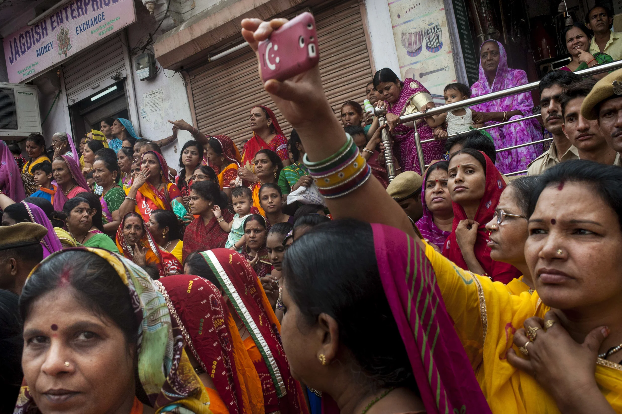   Women gather together in the back of the crowd behind male parade goers to watch the Krishna festival parade in Udaipur on July 17, 2015. Public space, by definition, are areas designated to be accessible to all individuals. However, separation of 