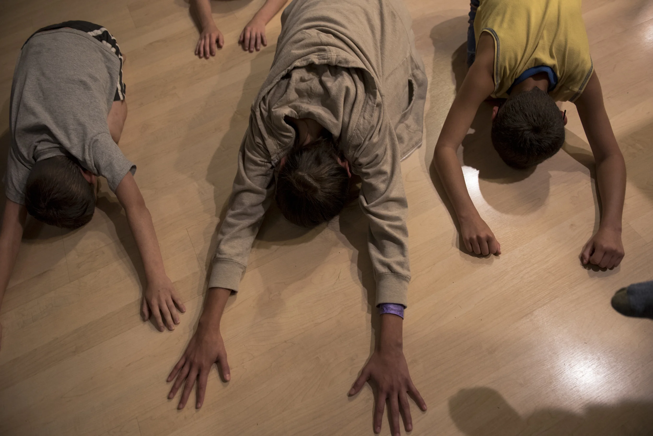  From left to right, Liam, Olivia, and Sean practice yoga with their mother in their living room. DJ teaches her children many different practices for healing, such as yoga and trauma release exercise (TRE). "How can I help these kids overcome and pu