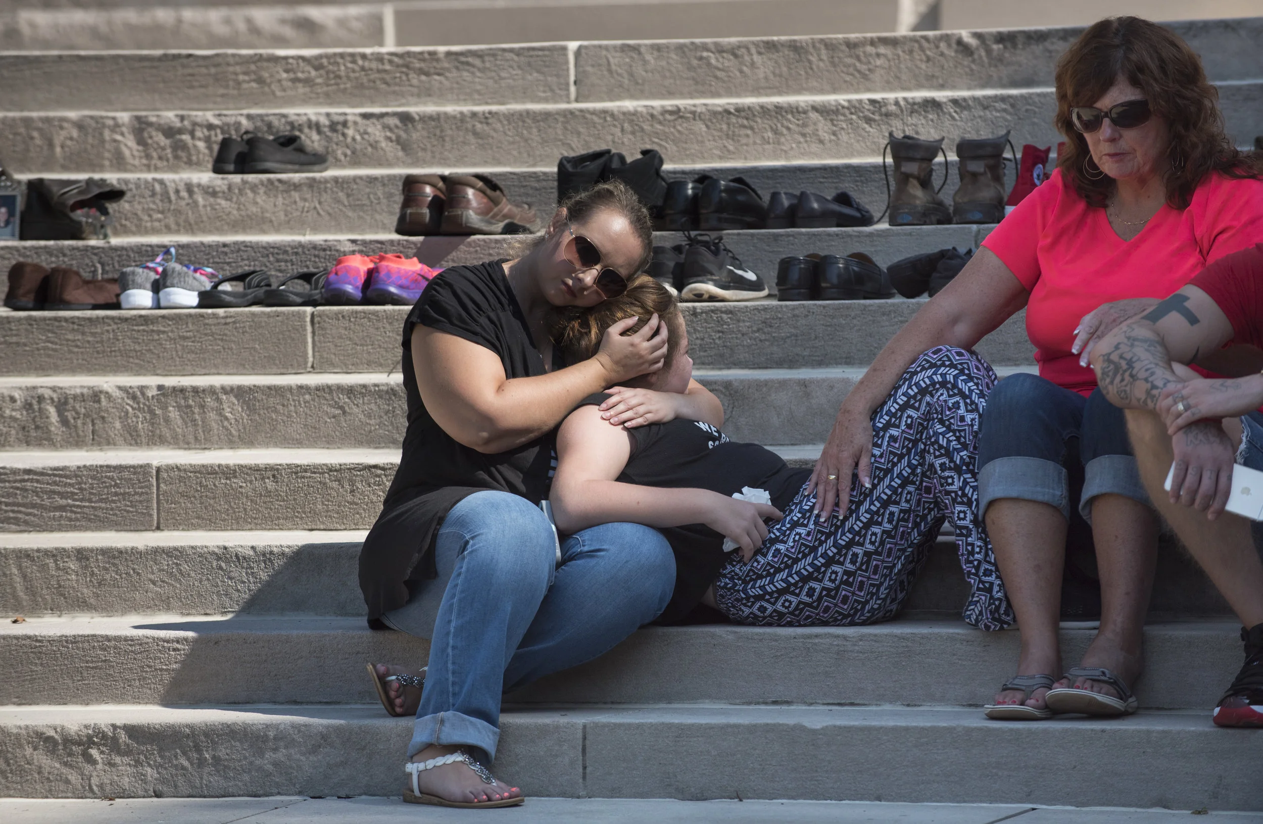 Lauri Martin, left, and Gale McComas, right comfort Abigale Boling, 11, on the State Capitol steps during the West Virginia Overdose Awareness Day Tribute in Charleston, WV on August 27, 2016. Abigale lost both of her parents to heroine overdoses and has lived with her grandmother Gale since she was three weeks old. Abigale's father Travis Boling passed away less than two months ago on July 7, and her mother Shana Weekly passed away a little over two years ago. 