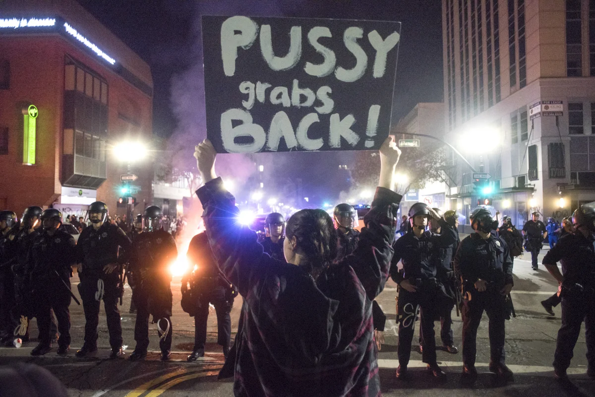 Destinee Yarrow holds up a sign reading "Pussy grabs back!" to Oakland riot police during an anti-Trump protest in downtown Oakland on November 9, 2016.