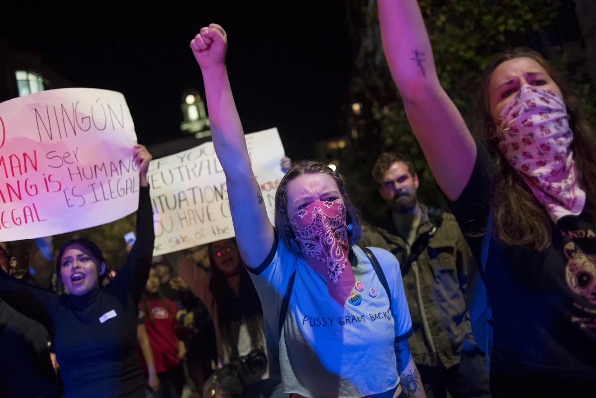 Sydney Hausken, middle, and Chandler James, right, students of San Francisco State, march in downtown Oakland in protest of President-elect Donald Trump on November 10, 2016.