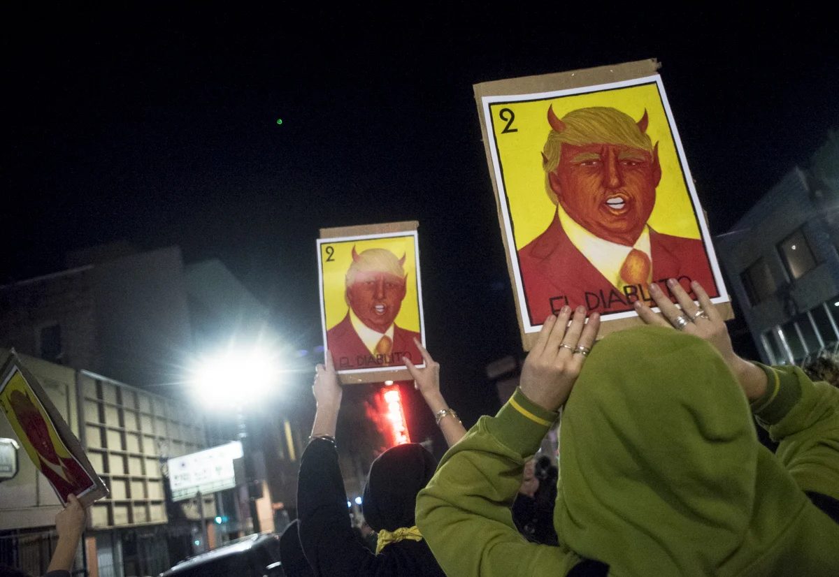 Protesters hold up signs reading "El Diablito" (the little devil) during an anti-Trump protest in downtown Oakland on November 10, 2016.