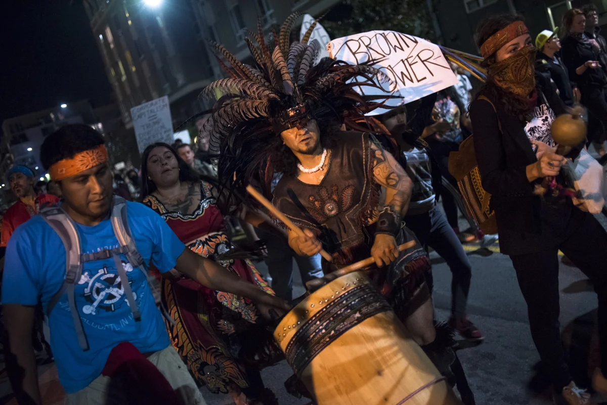 Performers dance and drum through the streets of downtown Oakland as part of the anti-Trump protest that took place on November 10, 2016.