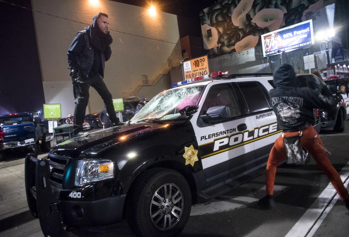 Anti-Trump protesters demolish a Pleasanton Police car in downtown Oakland on November 9, 2016. The peaceful protest escalated to property damage and street fires late into the night.