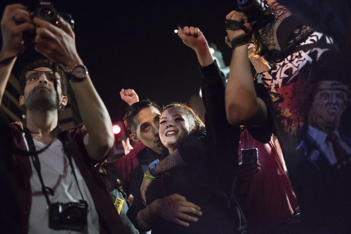 Kayla Corelovo and Kevin Garcia, middle, embrace during a chant at the anti-Trump protest in downtown Oakland on November 10, 2016.