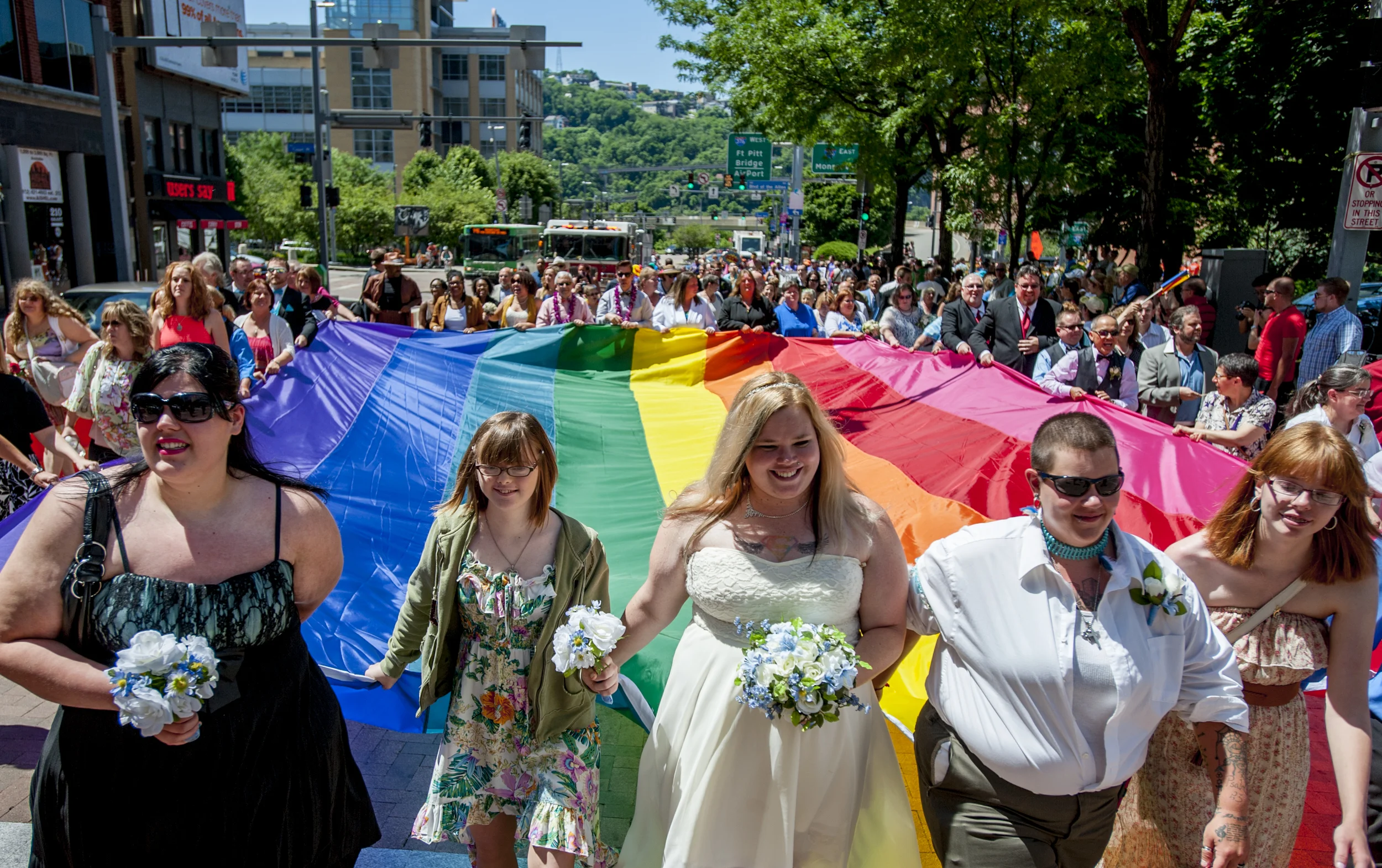  Just-married couples line the outside of a rainbow flag at the front of the 2015 Pittsburgh Pride Parade. The morning of the parade, 80 LGBTQ couples were married by Pittsburgh Mayor Bill Peduto at the city courthouse. 