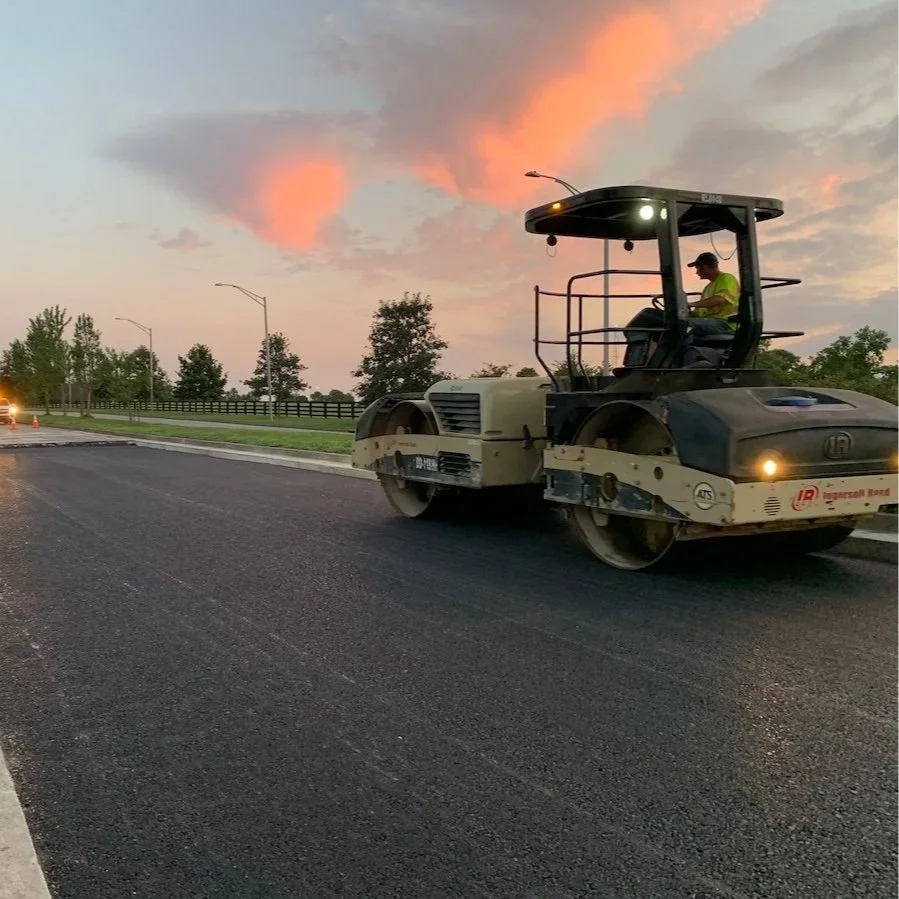 road roller paving asphalt during sunset