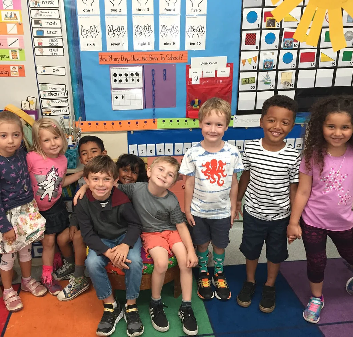 diverse group of kindergartners smiling in a classroom