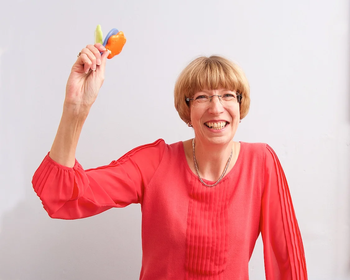 Posture and ergonomics expert Alison smiling and holding a hand clapper