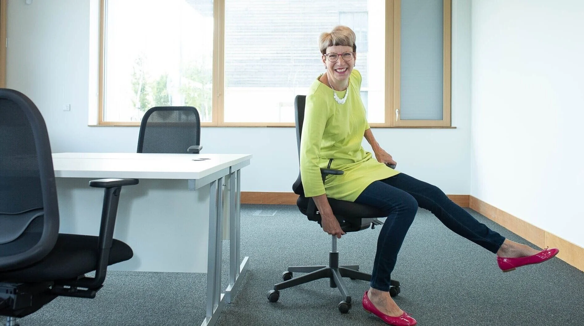 Posture elf Alison sitting on an office chair and making adjustments