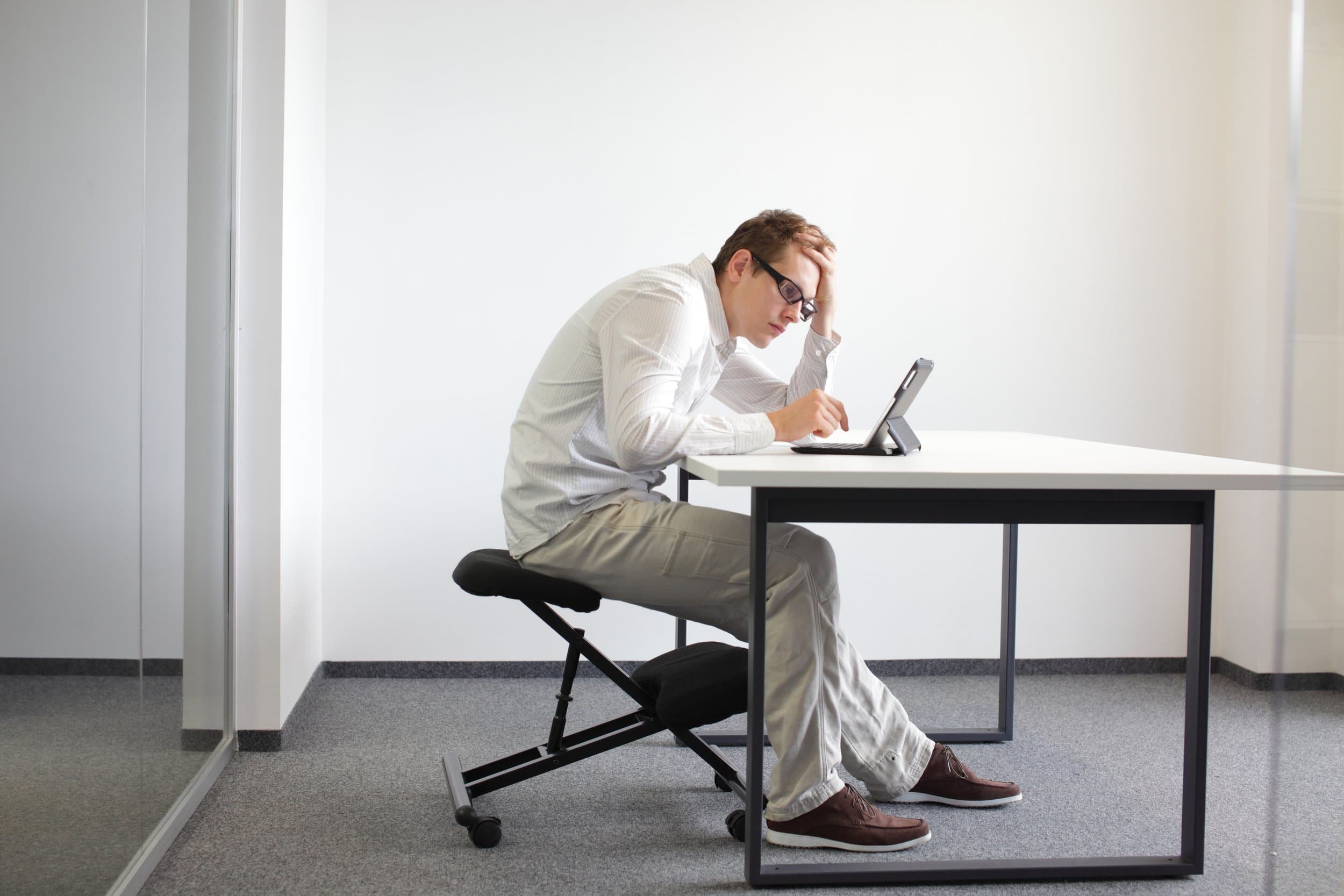 Man slumping over a laptop at a desk