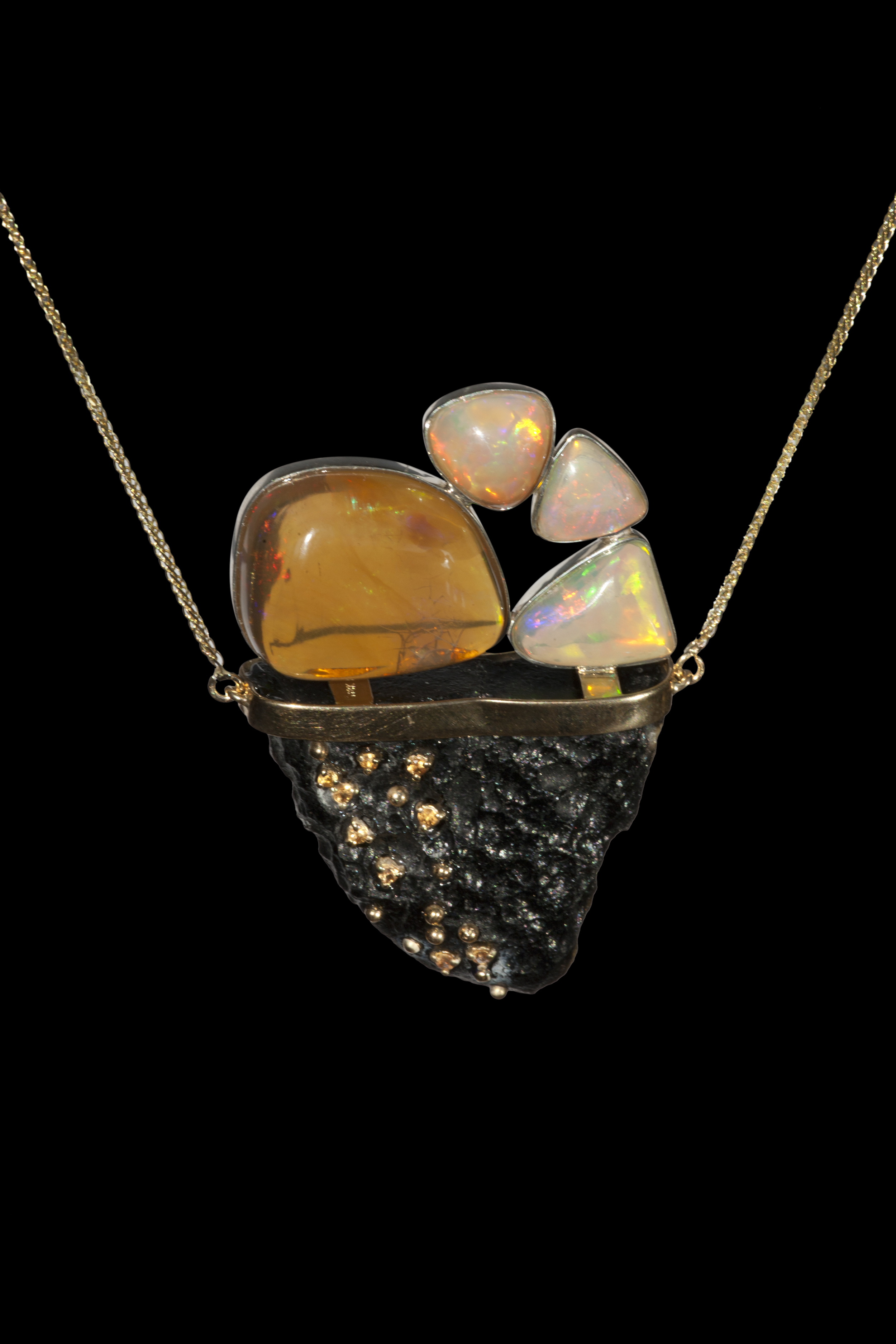 On a swing of Chinese tektite balances a large crescent fire opal from Ethiopia and 3 Ethiopian Wallo opals, with yellow sapphire pavé