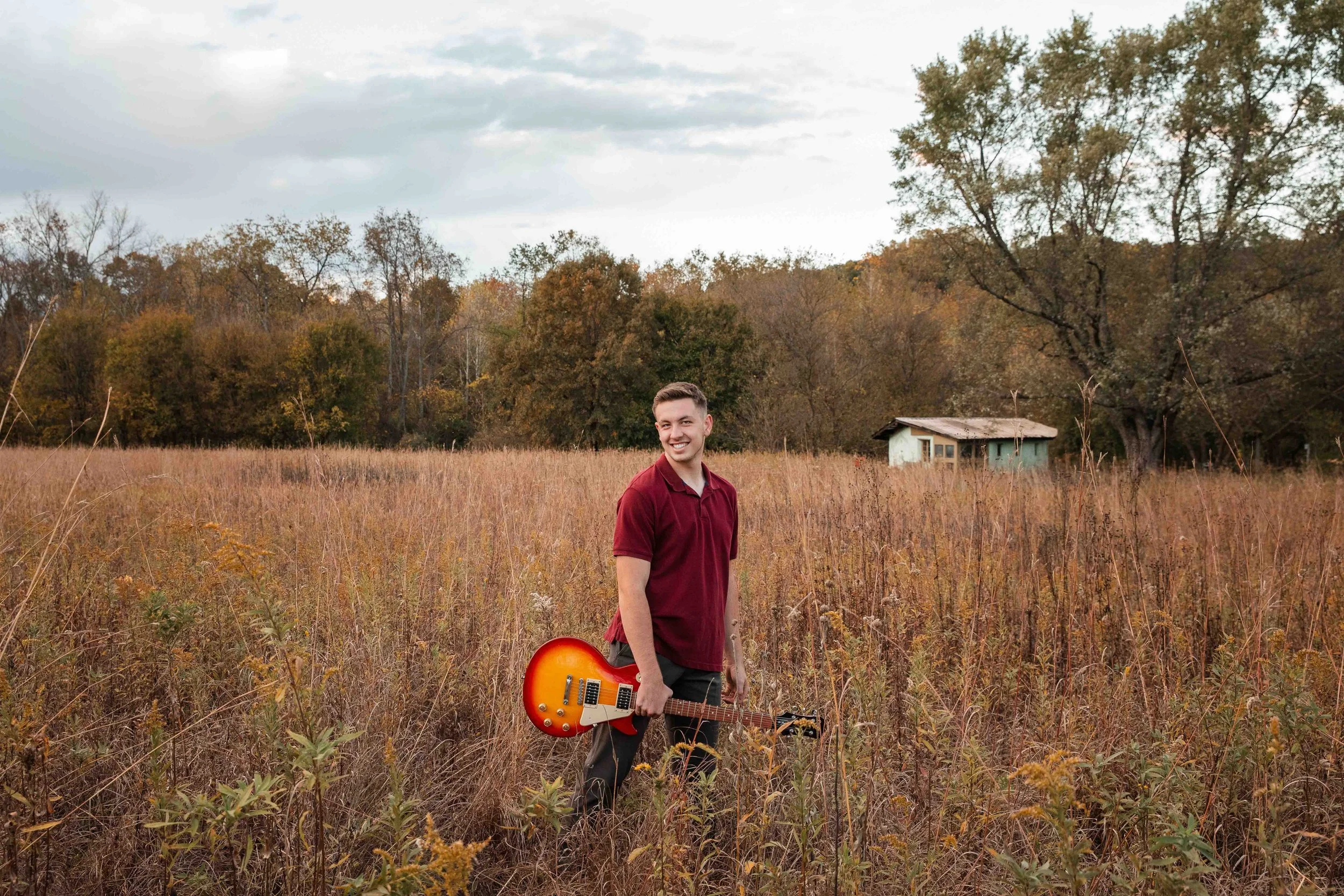 High school senior looking cool with a guitar in a field in Gambier, Ohio.