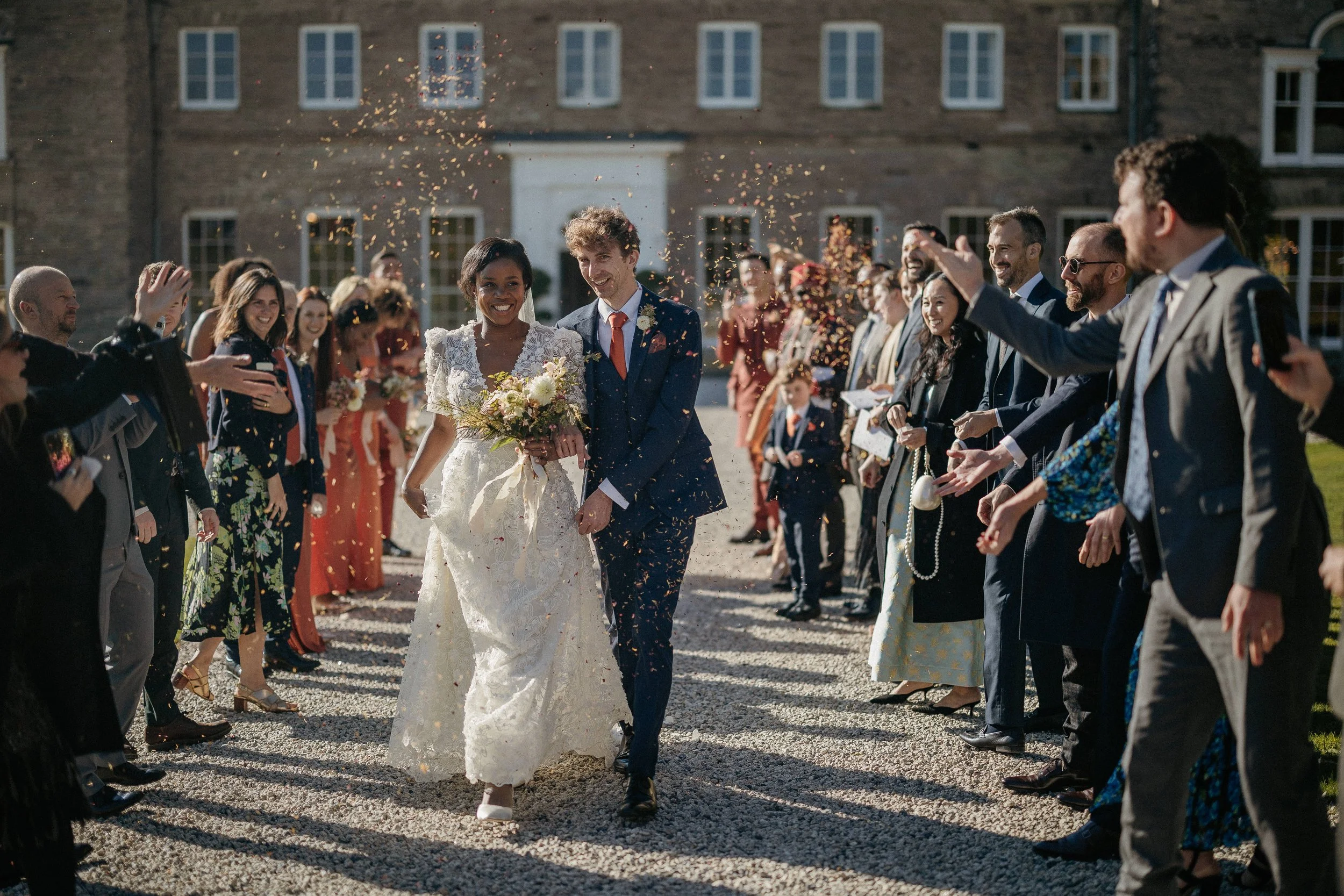 Decorative birthday table with cake, cupcakes, balloons, candles, and flowers against a brick wall