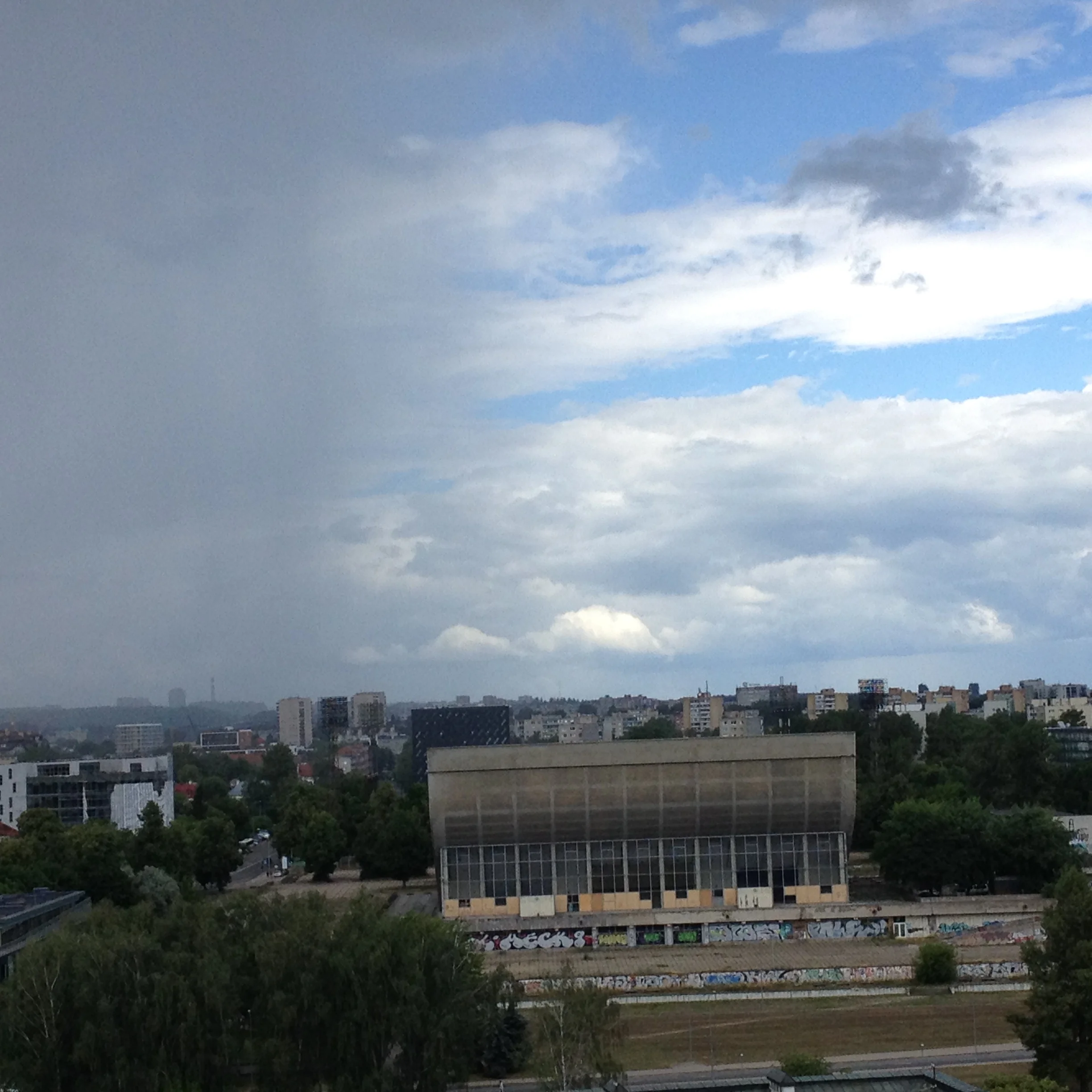 Rain coming close to huge concrete building with graffiti.