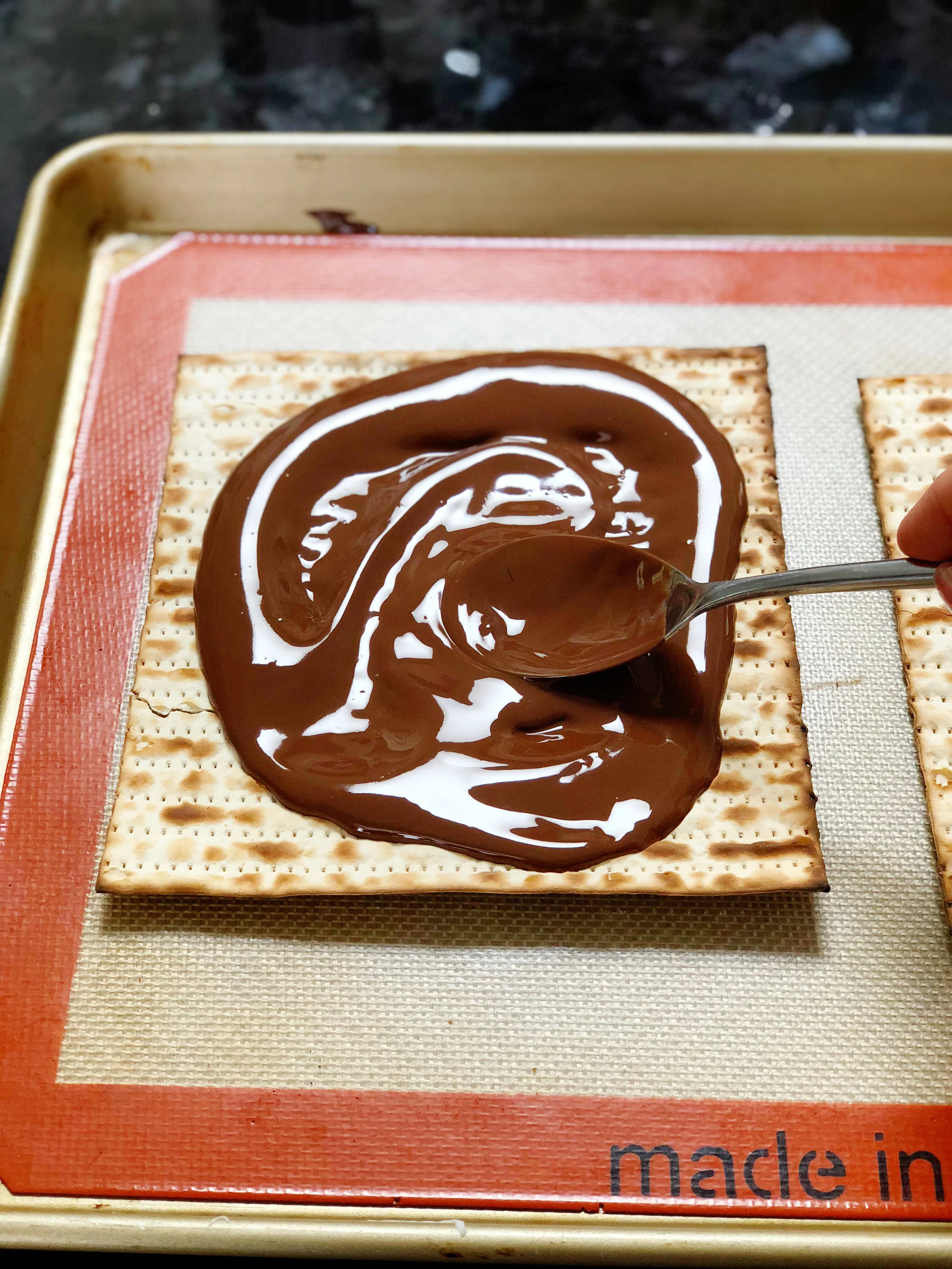 5. Now, pour half the chocolate mix over each matzah and spread around in an even layer with a spoon or spatula. 