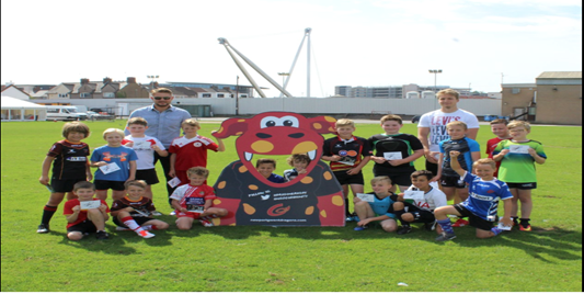 Wales international Tyler Morgan and Dragons captain Lewis Evans with participants of the Dragons Summer Skills Camp