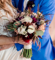 Close-up of a bride holding a colorful bouquet at a wedding.