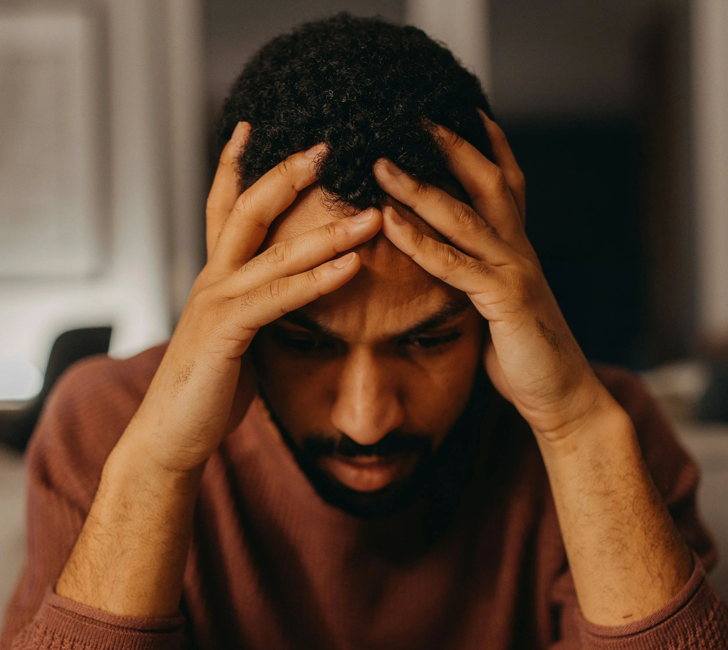 Man holding his head with both hands, appearing overwhelmed and distressed