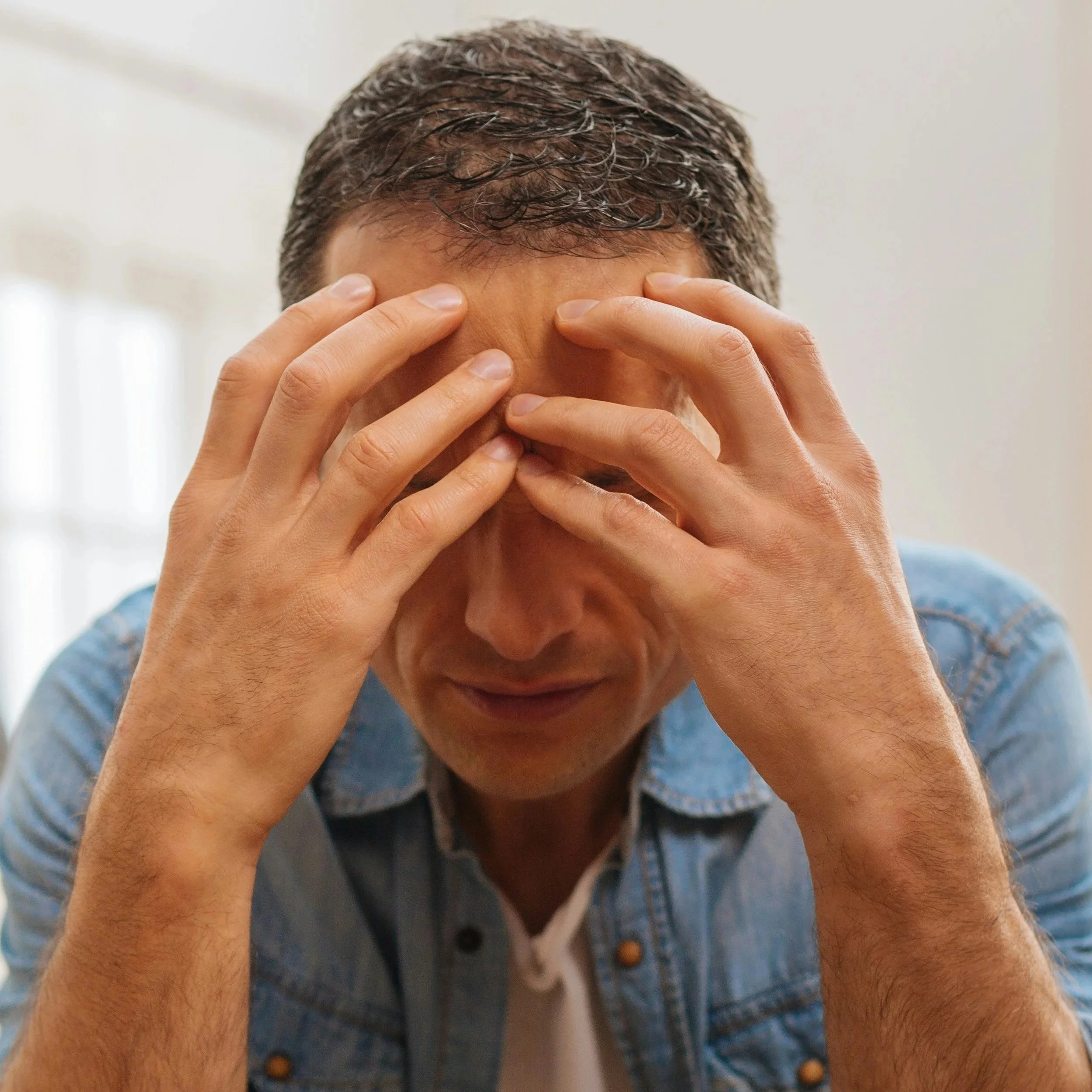 Man covering his face while appearing emotionally distressed