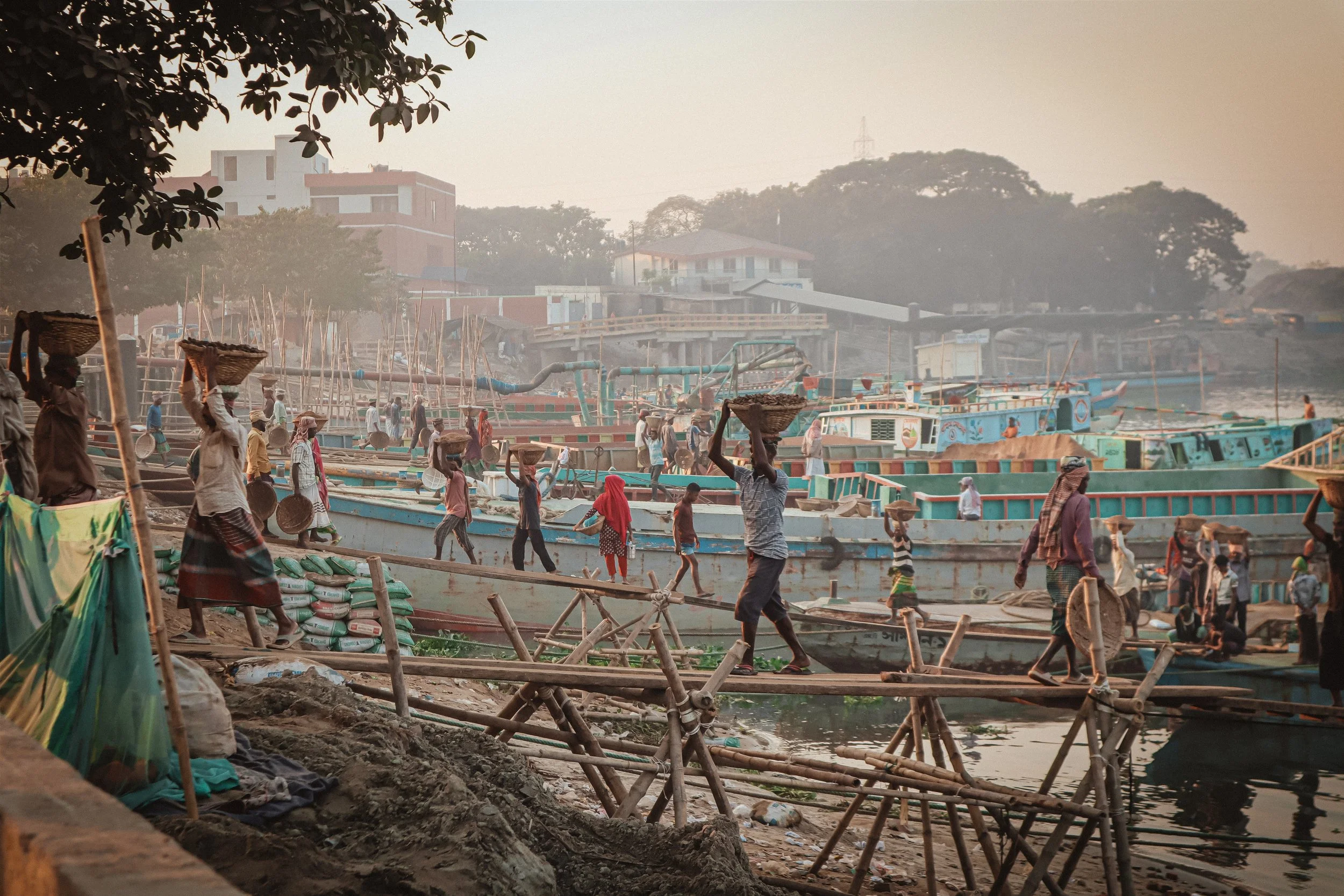 Migrant workers from rural Bangladesh transfer loads of coal from ships onto the shore for survival income.